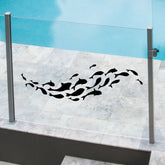 A black school of fish sticker on a clear glass pool fence.